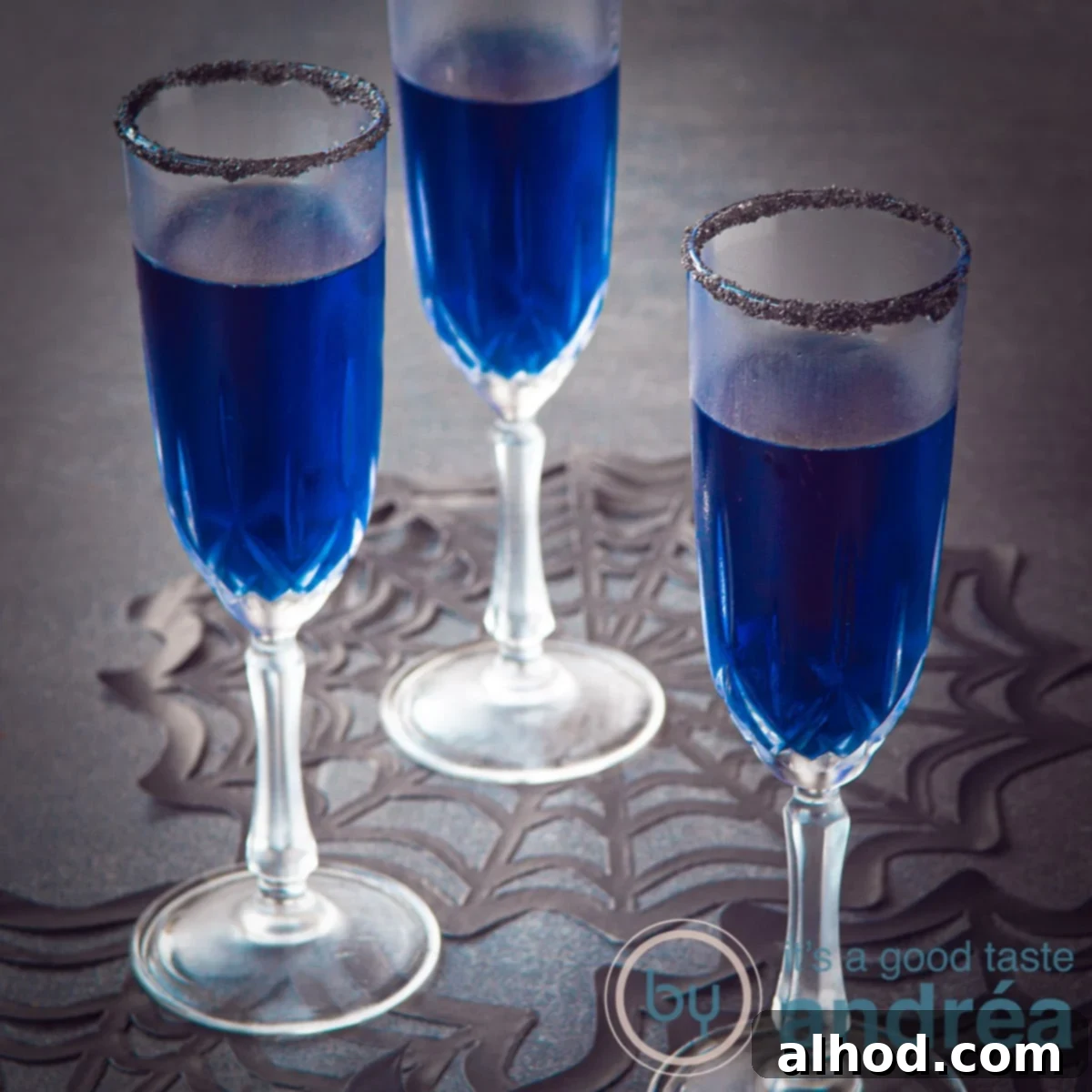 A square photo with three glasses filled with blue Halloween cocktails and a black rim, ready for a spooky celebration.