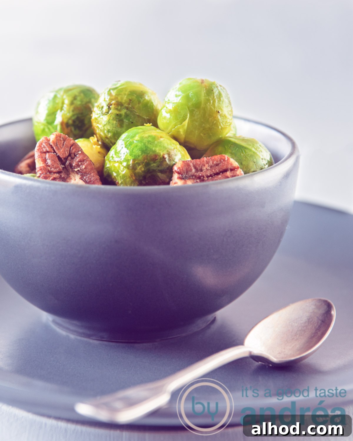 Zesty Orange Glazed Brussels Sprouts 5 Close-up of golden-brown Brussels sprouts glistening with orange glaze and sprinkled with pecans, served in an elegant dish.