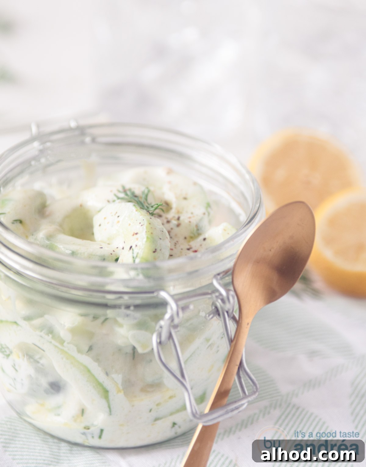 Authentic Tzatziki Recipe 4 A close-up shot of homemade tzatziki served in a stylish glass jar, accompanied by a golden spoon, emphasizing its creamy texture and fresh ingredients.