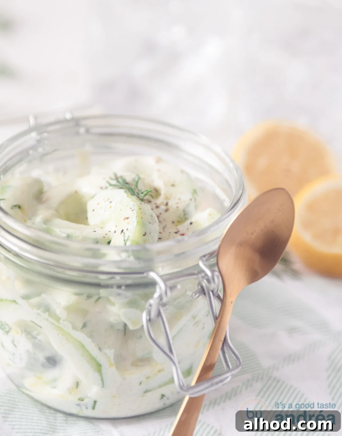 Refreshing Cucumber Yogurt Dip 4 Homemade tzatziki in a elegant glass with a golden spoon, ready to be served. The texture is creamy with visible cucumber pieces and fresh dill. This image highlights the deliciousness and homemade quality of the dish.