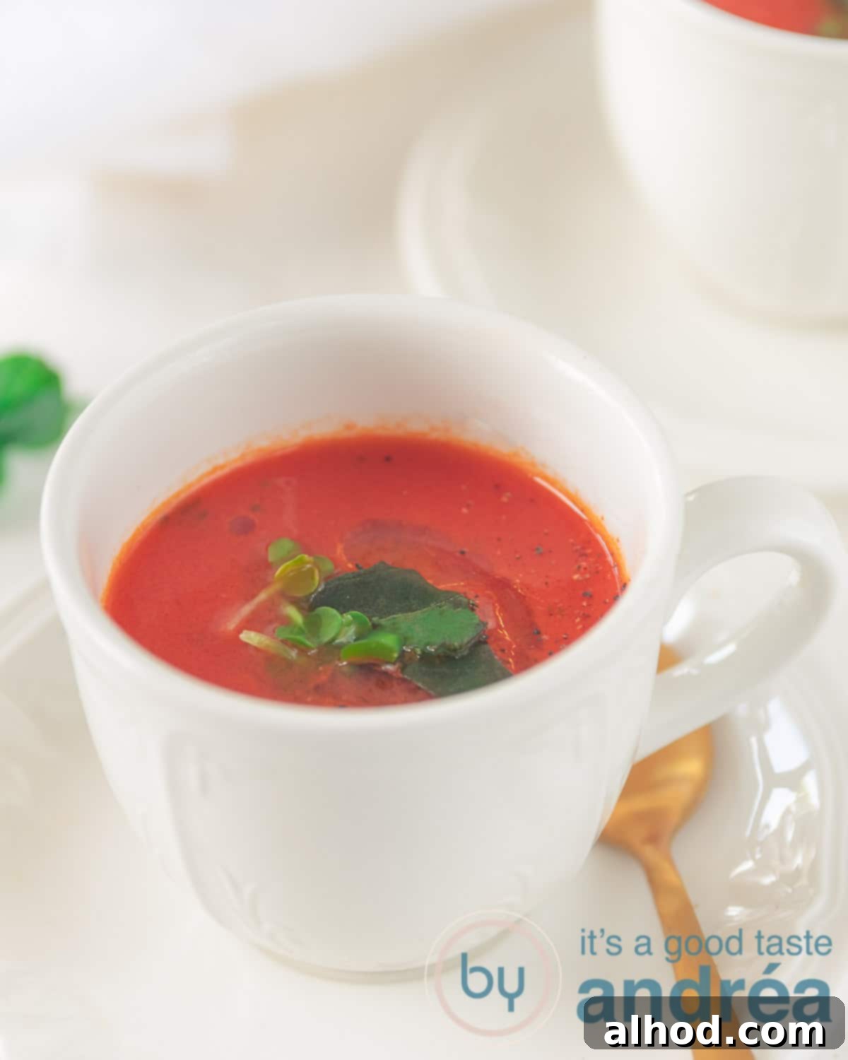 Garden Fresh Tomato Soup 2 A cup with a vegan, homemade tomato soup, garnished with fresh basil and a swirl of olive oil, ready to be enjoyed.