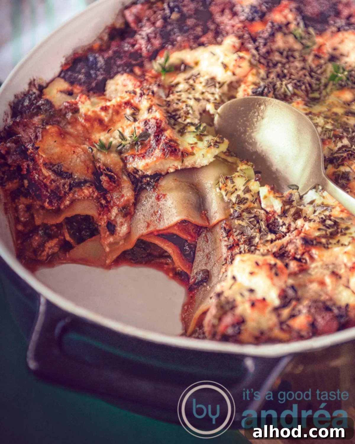 A close-up of a golden-brown, cheesy Sausage and Kale Lasagna, fresh out of the oven, with steam gently rising.