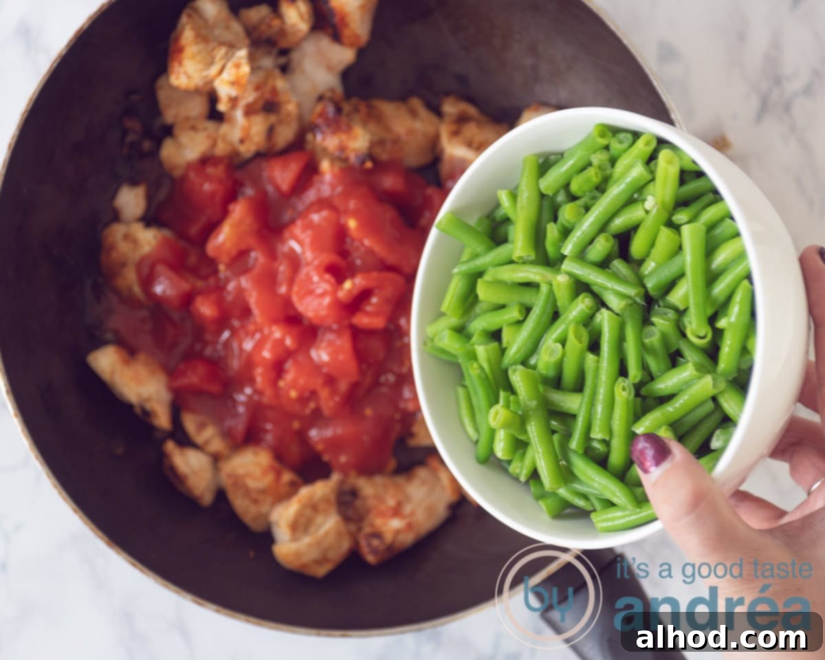 Loaded Chicken Nacho Bake 5 Aan de gebakken kipblokjes worden tomatenblokjes en sperziebonen toegevoegd