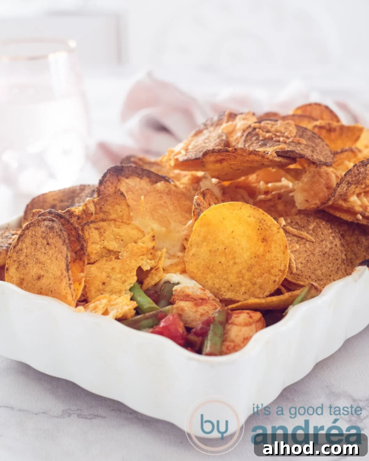 Loaded Chicken Nacho Bake 10 A height photo of a chicken nacho casserole with a filling of beans, chicken and tomato sauce on a white surface