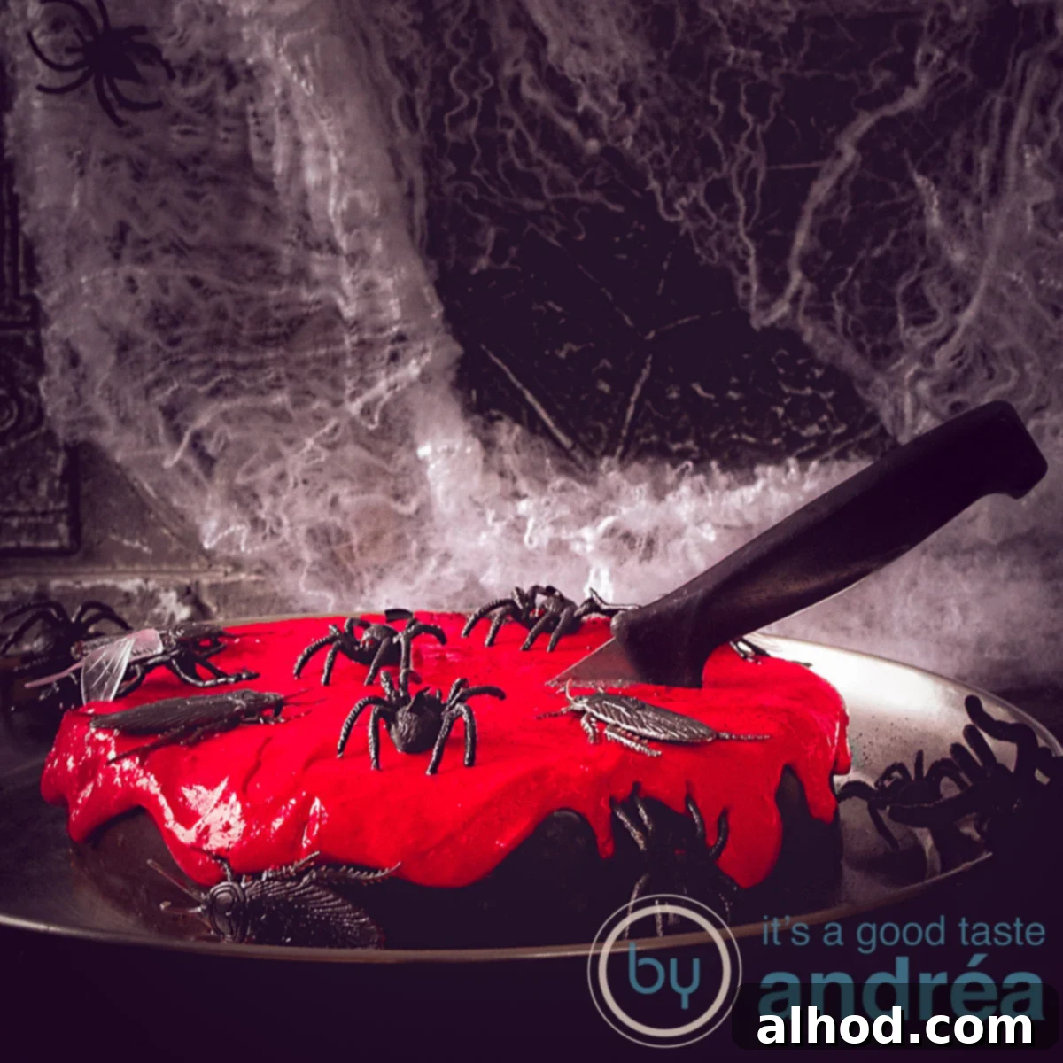 Ghoulishly Good Chocolate Cake 4 A square picture of a chocolate Halloween cake with a red cream cheese topping. Decorated with insects and knifes. A dark background