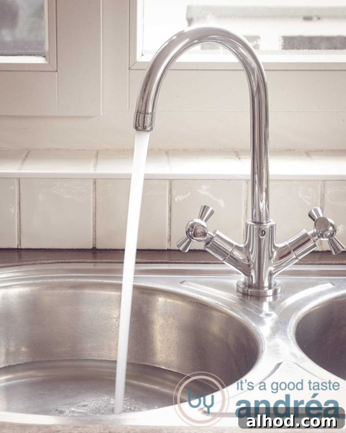 A stainless steel sink is filled with soapy water and dishes.
