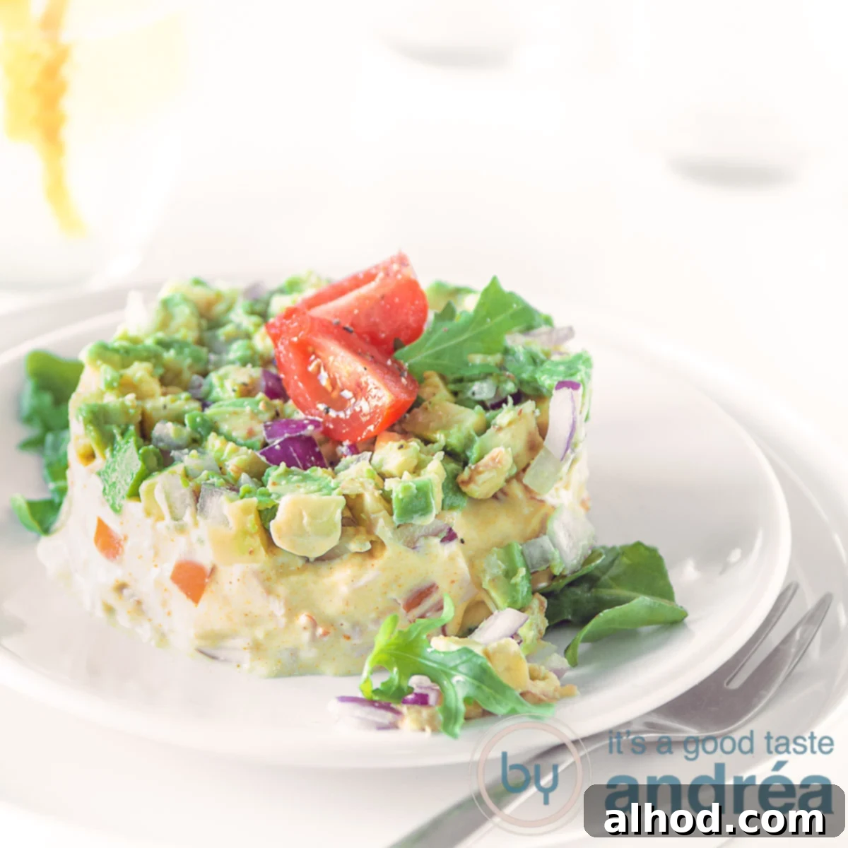 Smoky Chicken Avocado Bites 6 A square photo of a salad of smoked chicken and avocado on a white plate, topped with quartred cherry tomatoes on a white background
