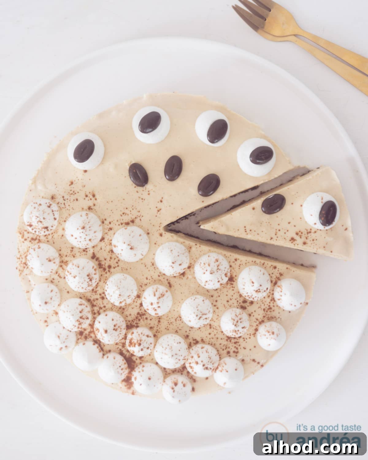Irish Coffee Cheesecake 2 A stunning overhead view of a creamy Irish Coffee Cheesecake with a slice elegantly cut out, revealing its smooth texture. It's presented on a pristine white cake plate, set against a clean white surface.