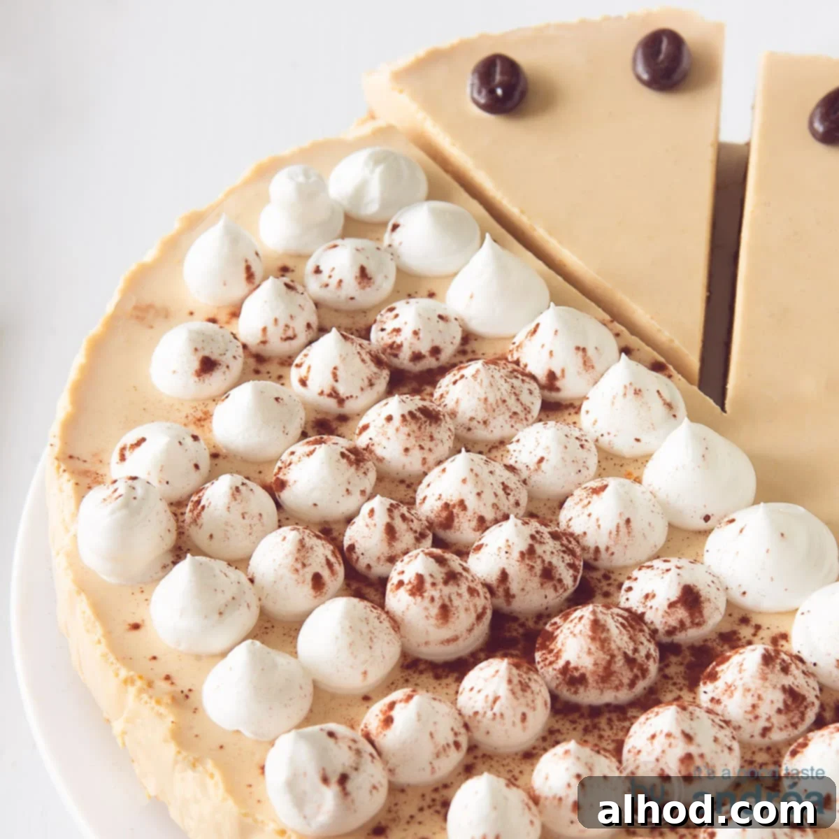 Decadent Irish Coffee Cheesecake 5 A square photo with part of an Irish Coffee tart cheesecake on a white surface. A point has been cut out at the top.
