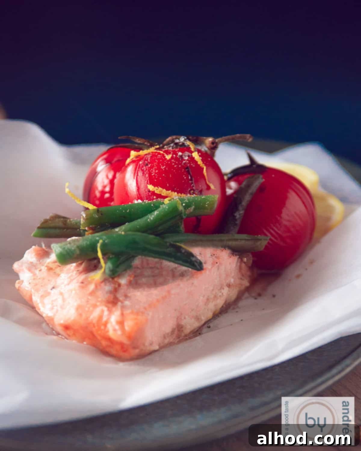 Oven-Baked Salmon Parcels 1 Beautifully steamed salmon fillet in a parchment paper packet, surrounded by vibrant green beans and juicy cherry tomatoes, garnished with fresh lemon.