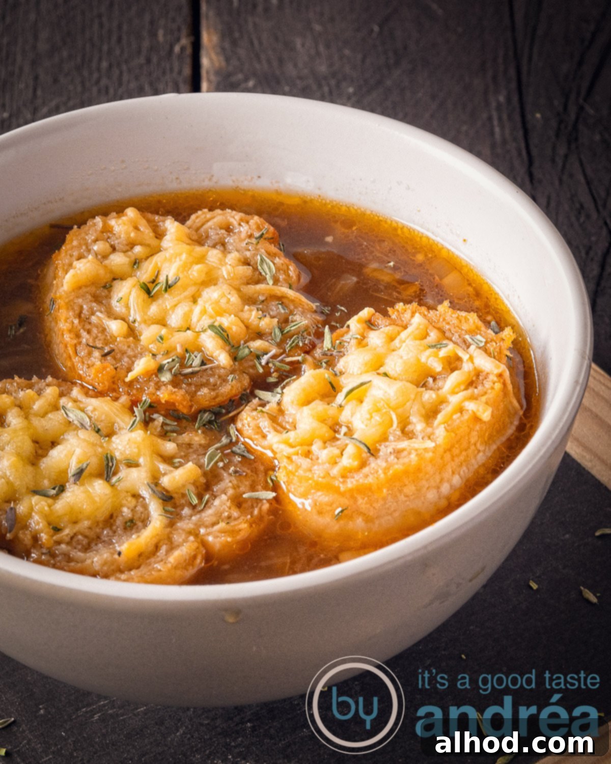 Savory Vegetarian French Onion Soup 2 A partial enlargement of a bowl of onion soup with three slices of gratinated baguette on a dark background