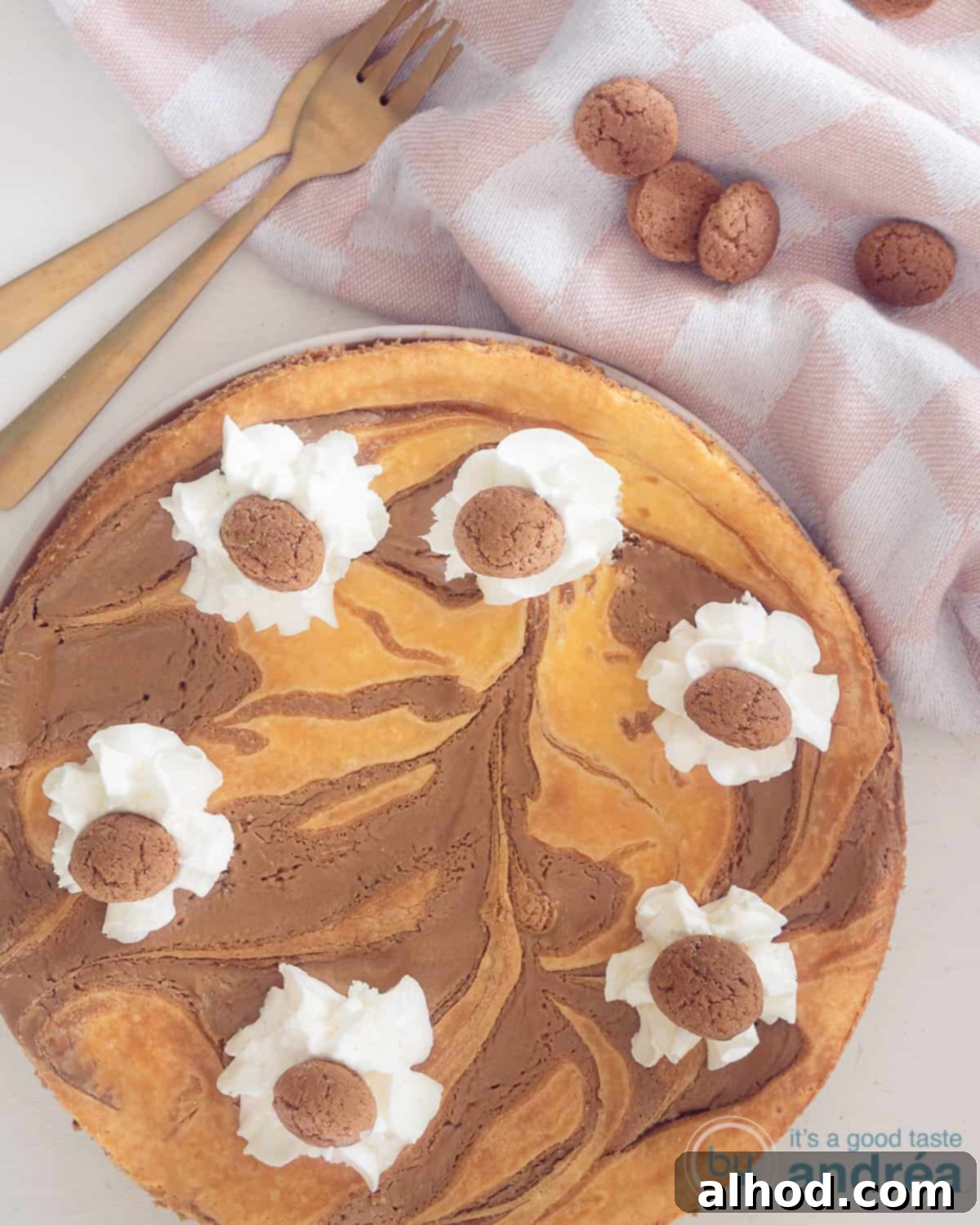 Sinterklaas Celebration Cheesecake 3 A photo from above. Bottom left a Sinterklaas Cheesecake topped with whipped cream and spiced nuts. Top right two golden forks, a pink white cloth and gingerbread nuts.