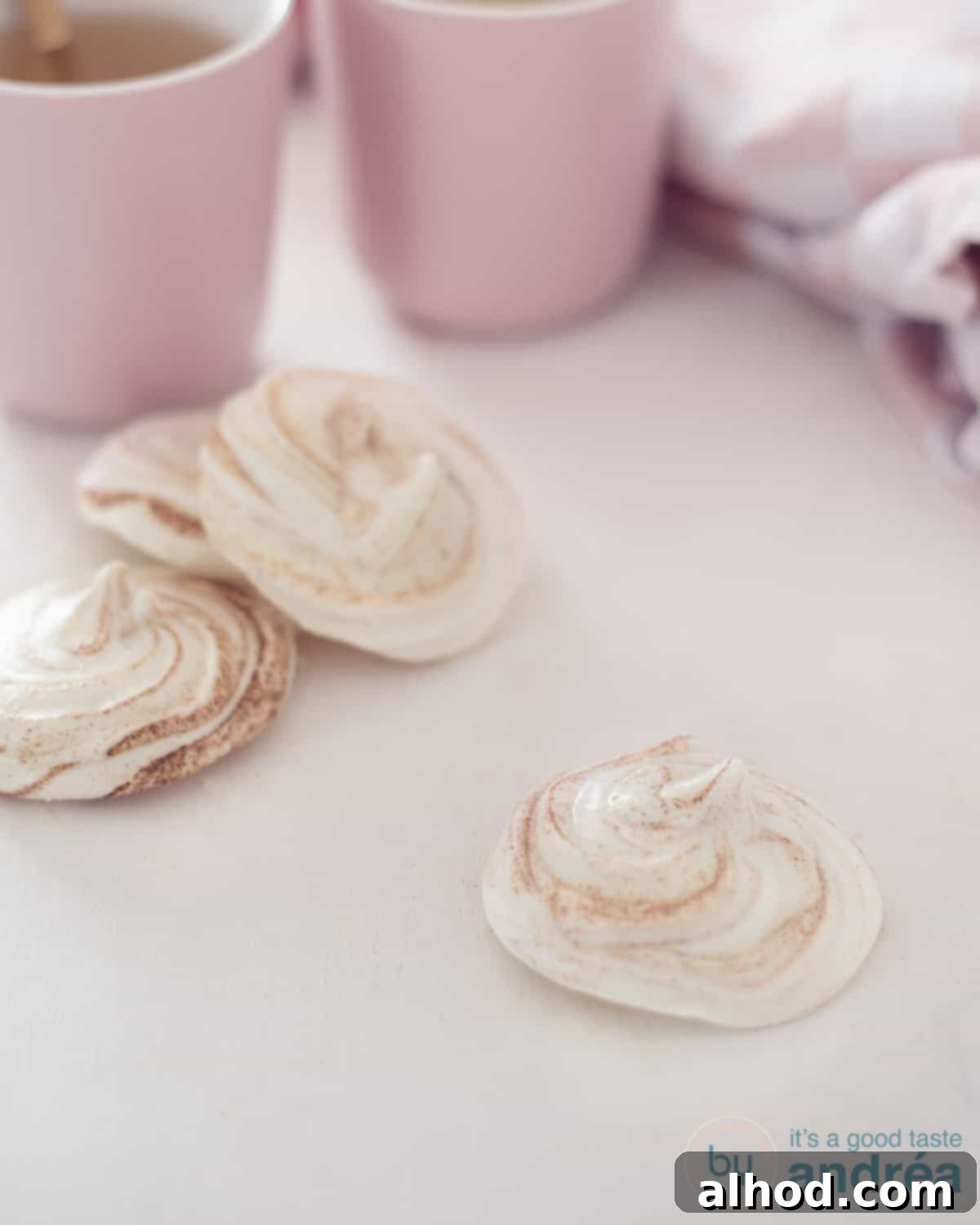 Snowy Kisses 3 Four Biscoff Meringues on a white background. In the back two pink jugs and a white pink cloth