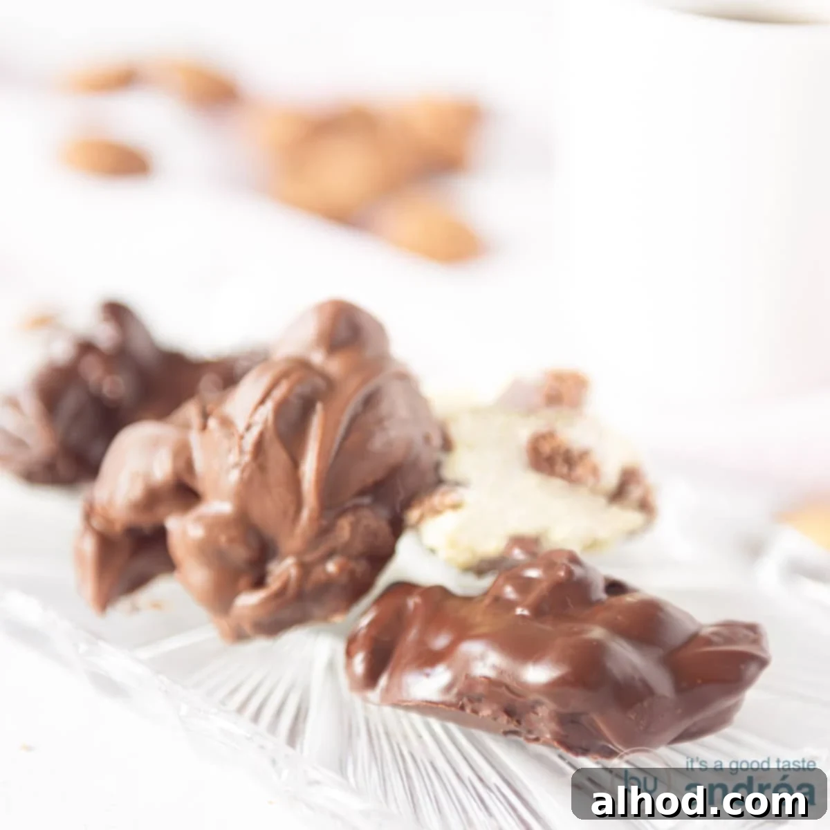 Spiced Pepernoten Chocolate Discs 6 Een vierkante foto met vier chocolade flikken op een glazen schaaltje. Pepernoten in de achtergrond.