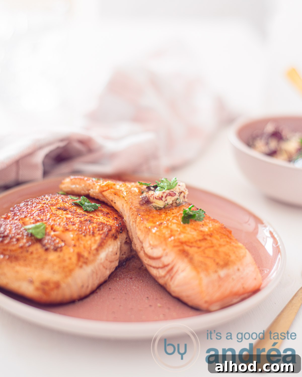 Close-up of a pan-fried salmon fillet steak with red wine herb butter, served on a pink plate, highlighting the rich colors and texture.