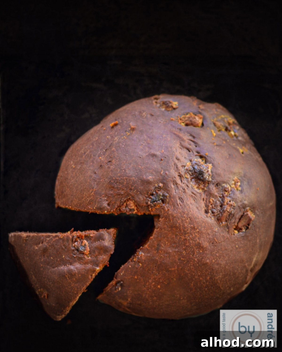 Artisan Double Chocolate Chunk Loaf 3 A top down picture of chocolate bread. A part loosened from the rest of the bread on a black background