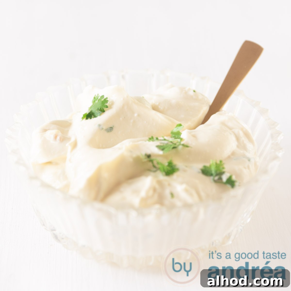 A bowl filled with homemade garlic sauce (aioli) with a golden spoon
