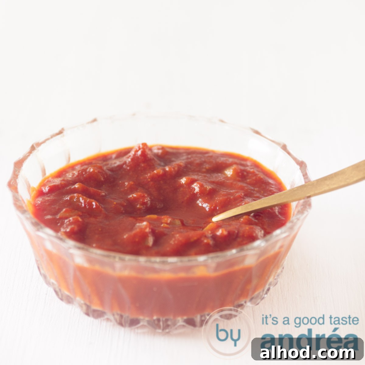 A glass bowl filled with homemade curry sauce with a golden spoon