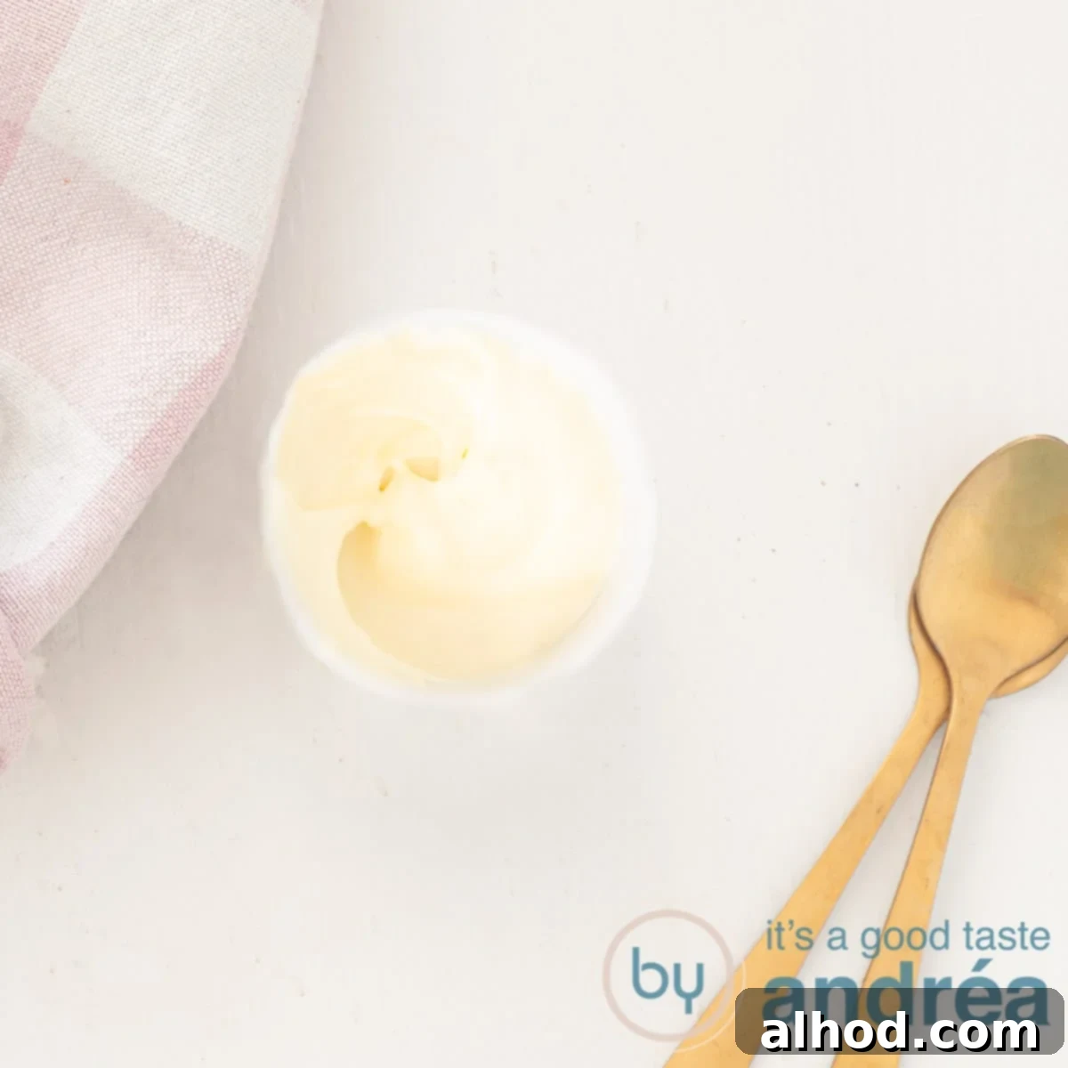 A square photo with a spoonful of yogurt mayonnaise, two golden spoons on the side