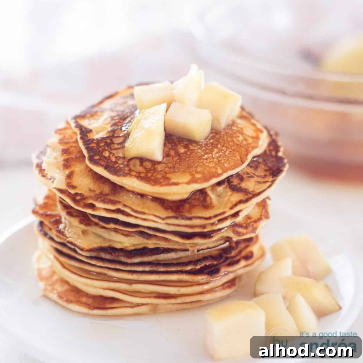 Poached Pear Pancakes 4 A square photo with a white plate with a stack of pancakes and stewed pears on top and around it.