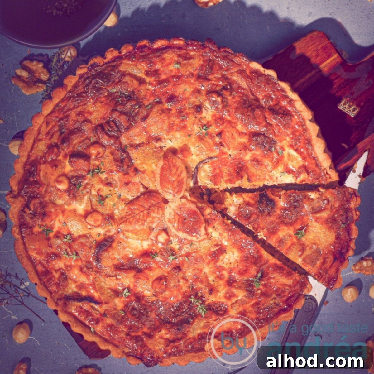 Sweet and Savory Pumpkin Sweet Potato Quiche with Roasted Garlic 6 A square photo of a quiche with a point cut out. A blue background where the quiche is located