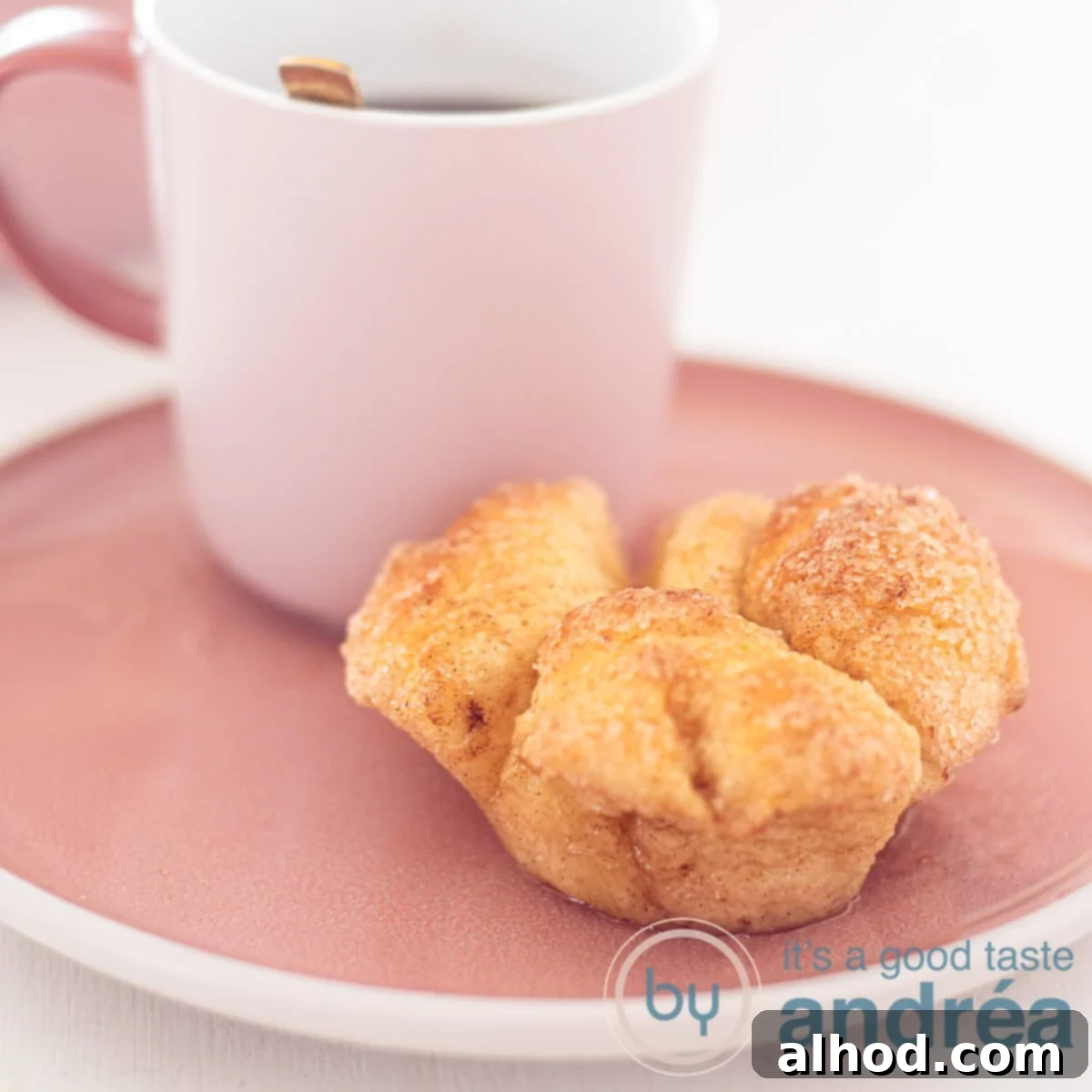 Pull-Apart Monkey Bread Muffins Recipe 6 A square photo of a pink plate with a cup of coffee and a monkey bread muffin in front of it.