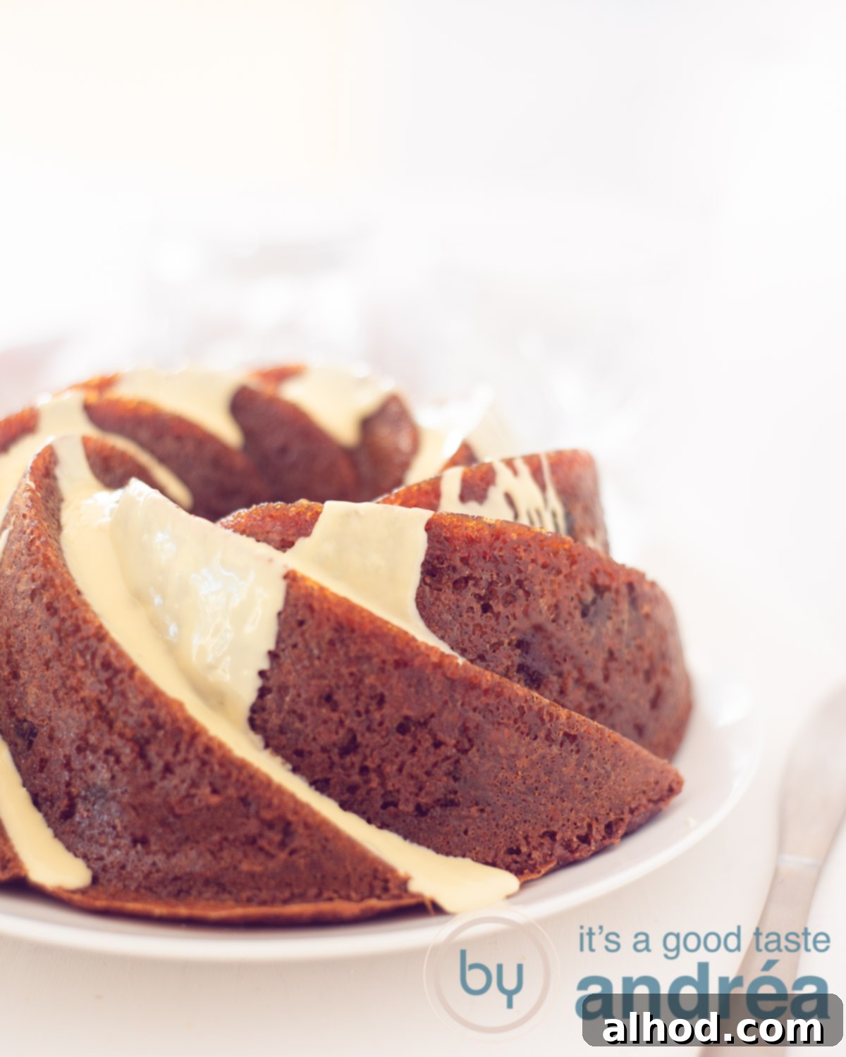 White Chocolate Cranberry Bliss Bundt 5 A part of a white chocolate cranberry bundt cake on a white plate on a white background