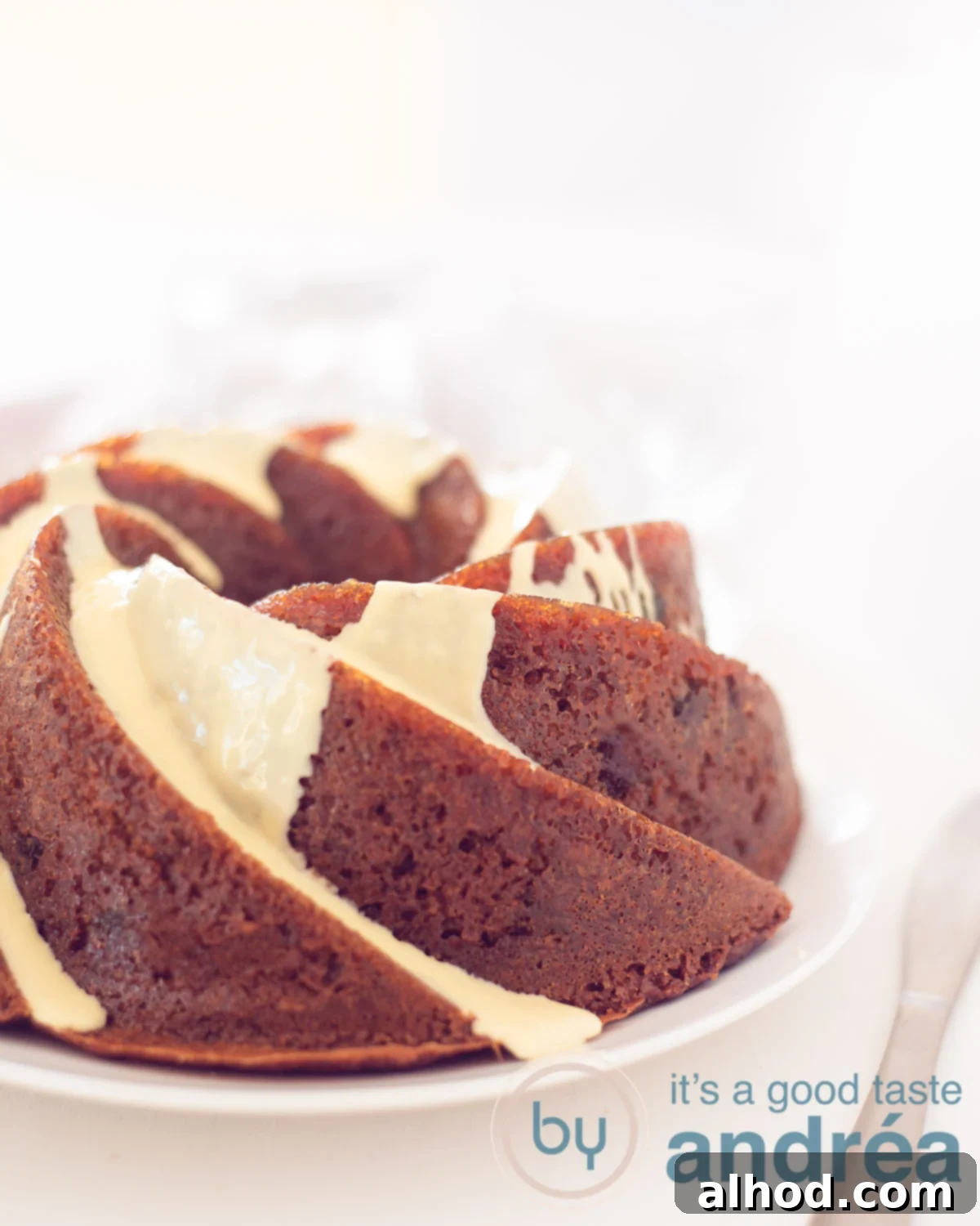 A close-up shot of a slice of White Chocolate Cranberry Bundt Cake on a white plate, showcasing the texture and white chocolate glaze.