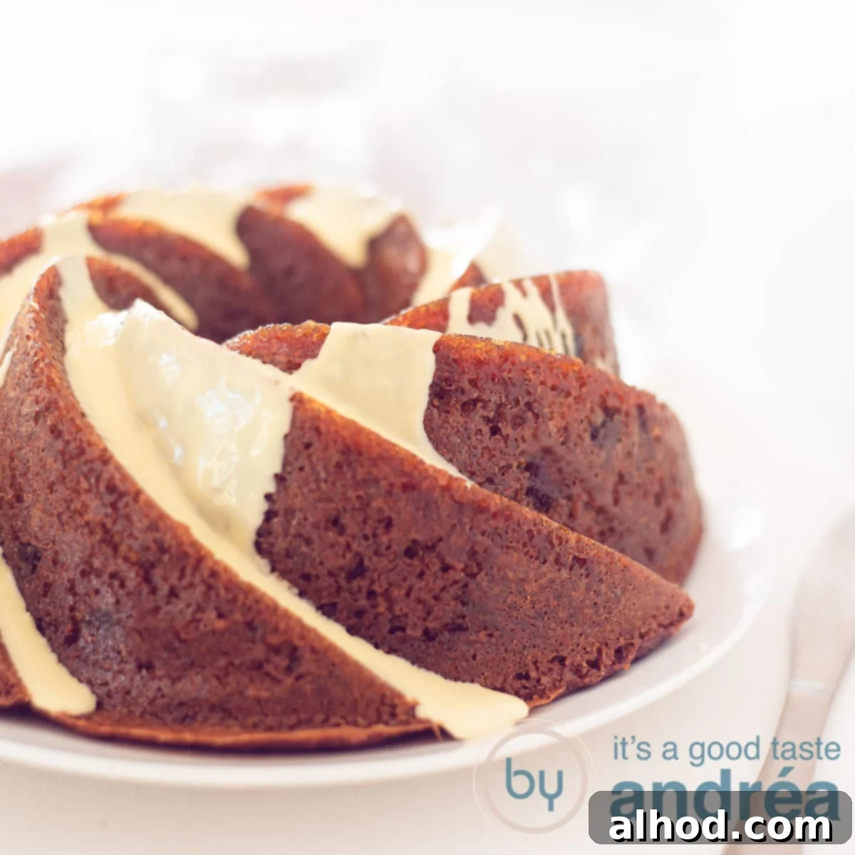 White Chocolate Cranberry Bliss Bundt 6 A square photo with part of a cranberry turban with white chocolate sauce. On a white plate on a white background. A golden knife lies to the right of it.