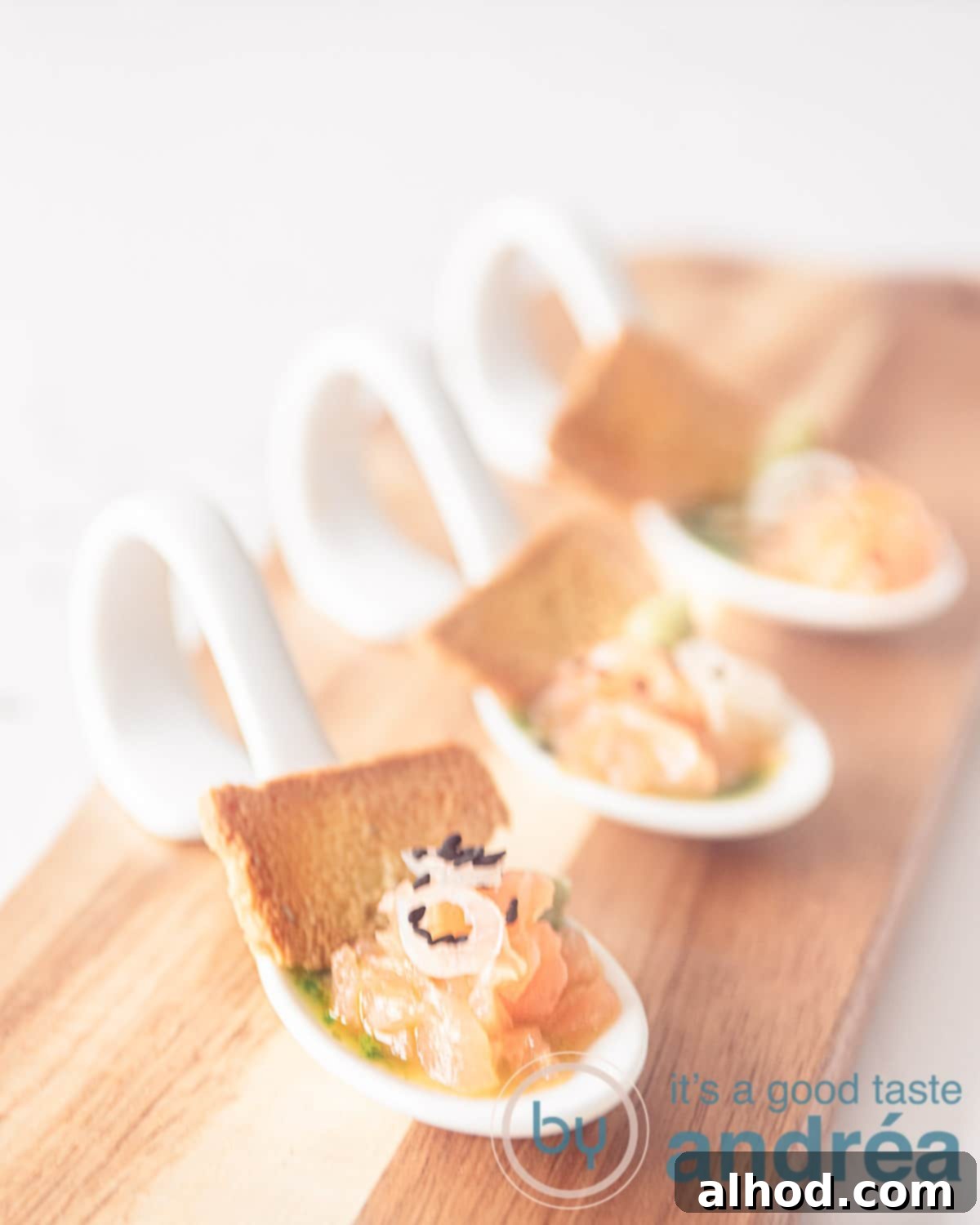 An elevation photo, three amuse-bouche spoons in a row filled with arugula oil, salmon and a toast