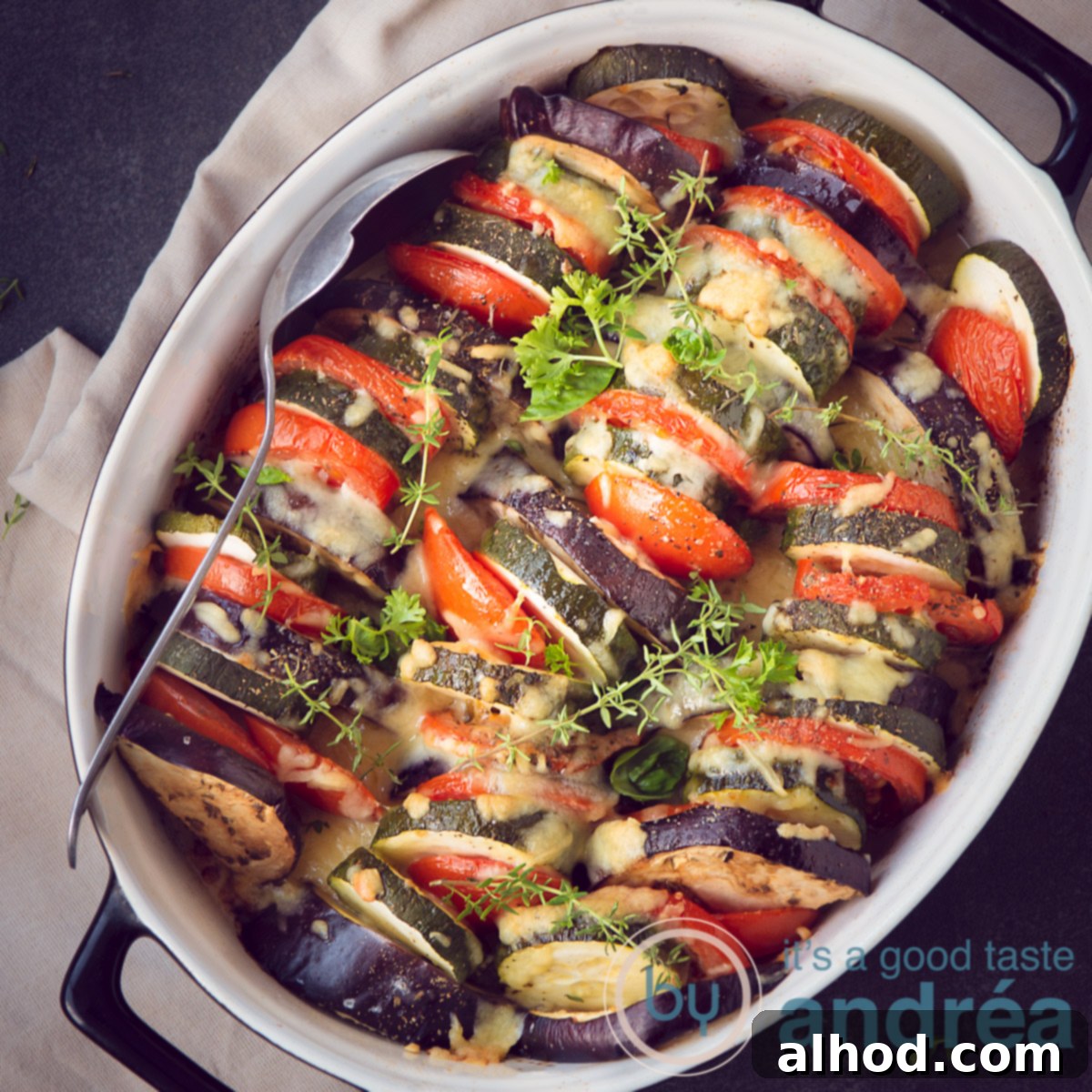 Unforgettable Yuletide Feast 8 A square oven dish filled with artfully arranged roasted vegetable slices, aromatic herbs, and a golden cheese gratin topping.
