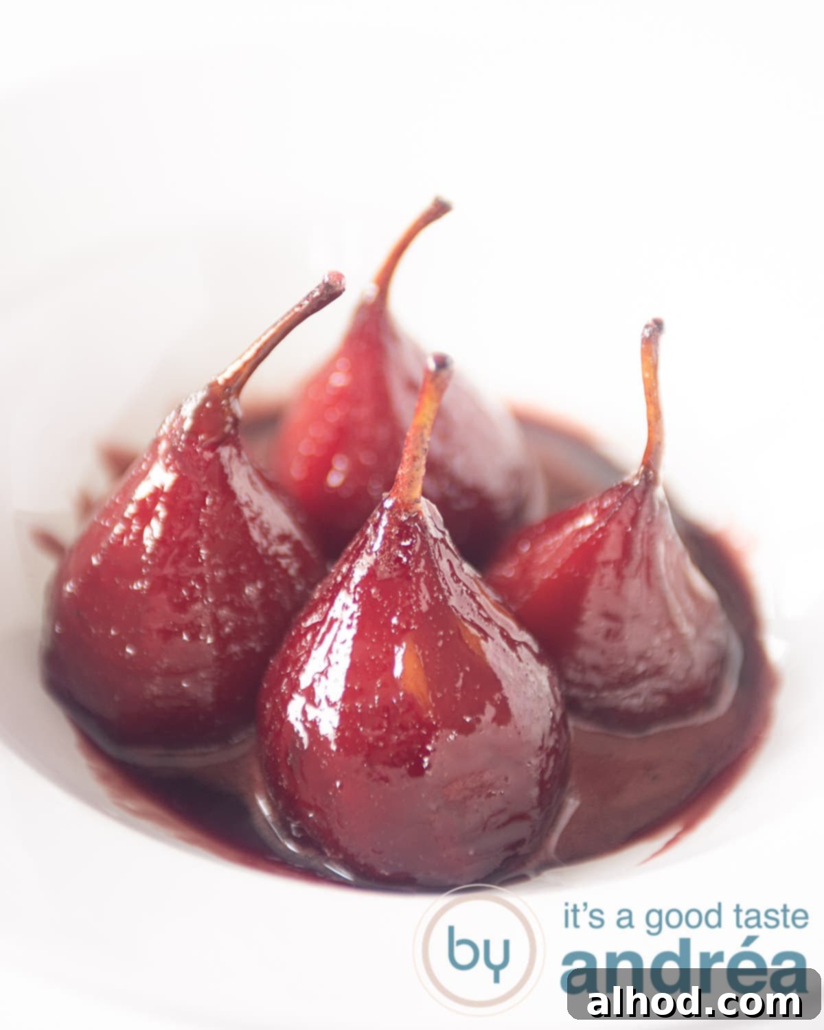 Effortless French Port Wine Poached Pears 2 Four poached pears with poaching syrup in a white deep plate