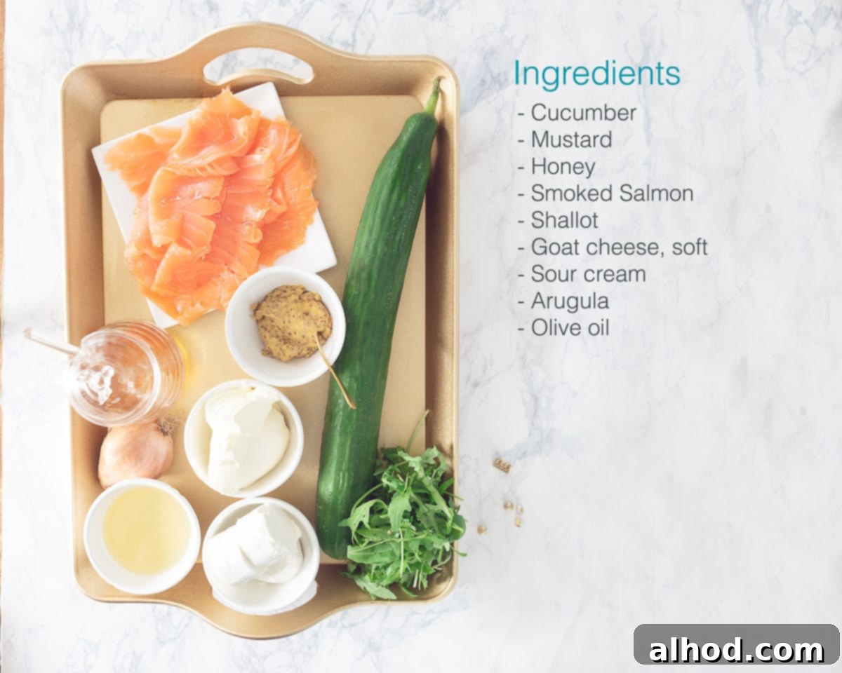 Gourmet Salmon and Chèvre Stacks 3 A golden tray holding all the fresh ingredients needed for Salmon and Goat Cheese Towers, including cucumber, honey, Dijon mustard, smoked salmon, shallots, goat cheese, sour cream, arugula, and olive oil.