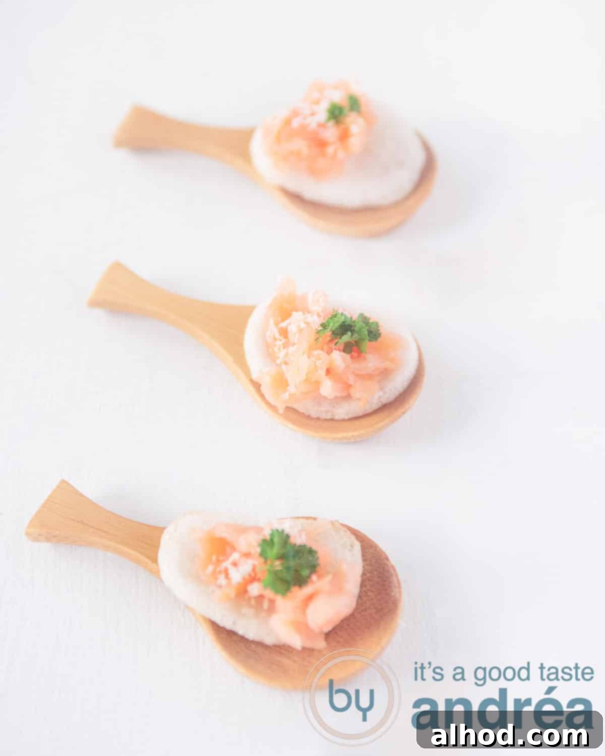 Salmon and Crispy Prawn Crackers 2 Three bamboo spoons in a row above each other with crispy prawn crackers topped with smoked salmon and fresh parsley. All arranged neatly on a pristine white background, showcasing the vibrant colors of the ingredients.