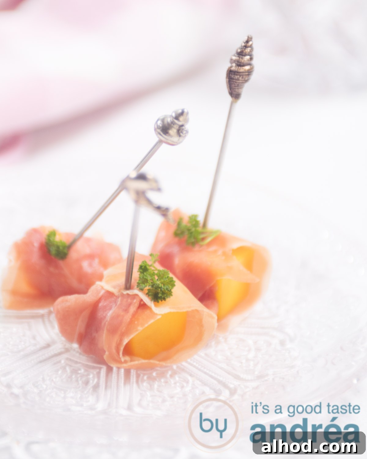 Prosciutto-Wrapped Mango Bites 5 A glass plate with three appetizers with mango and prosciutto