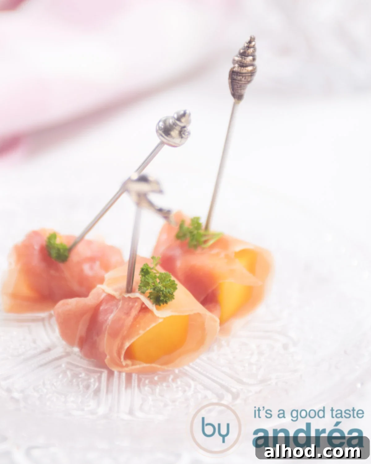 A glass plate with three appetizers with mango and prosciutto, elegantly arranged.