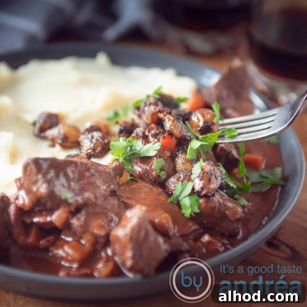 Slow Cooker Beef Bourguignon Without Mushrooms 6 A square photo with a gray plate, mashed potatoes, French beef bourguignon with parsley.