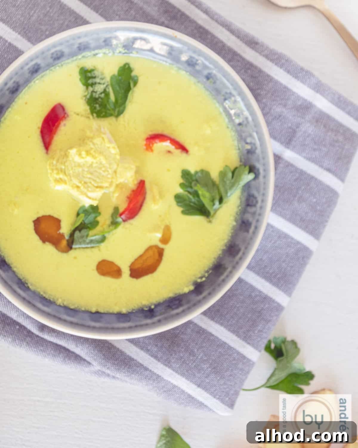 Velvety Ginger Coconut Chicken Soup 2 A top-down photo of a gray bowl filled with creamy coconut chicken soup, garnished with fresh herbs and spices, showcasing the rich texture and tender chicken pieces.