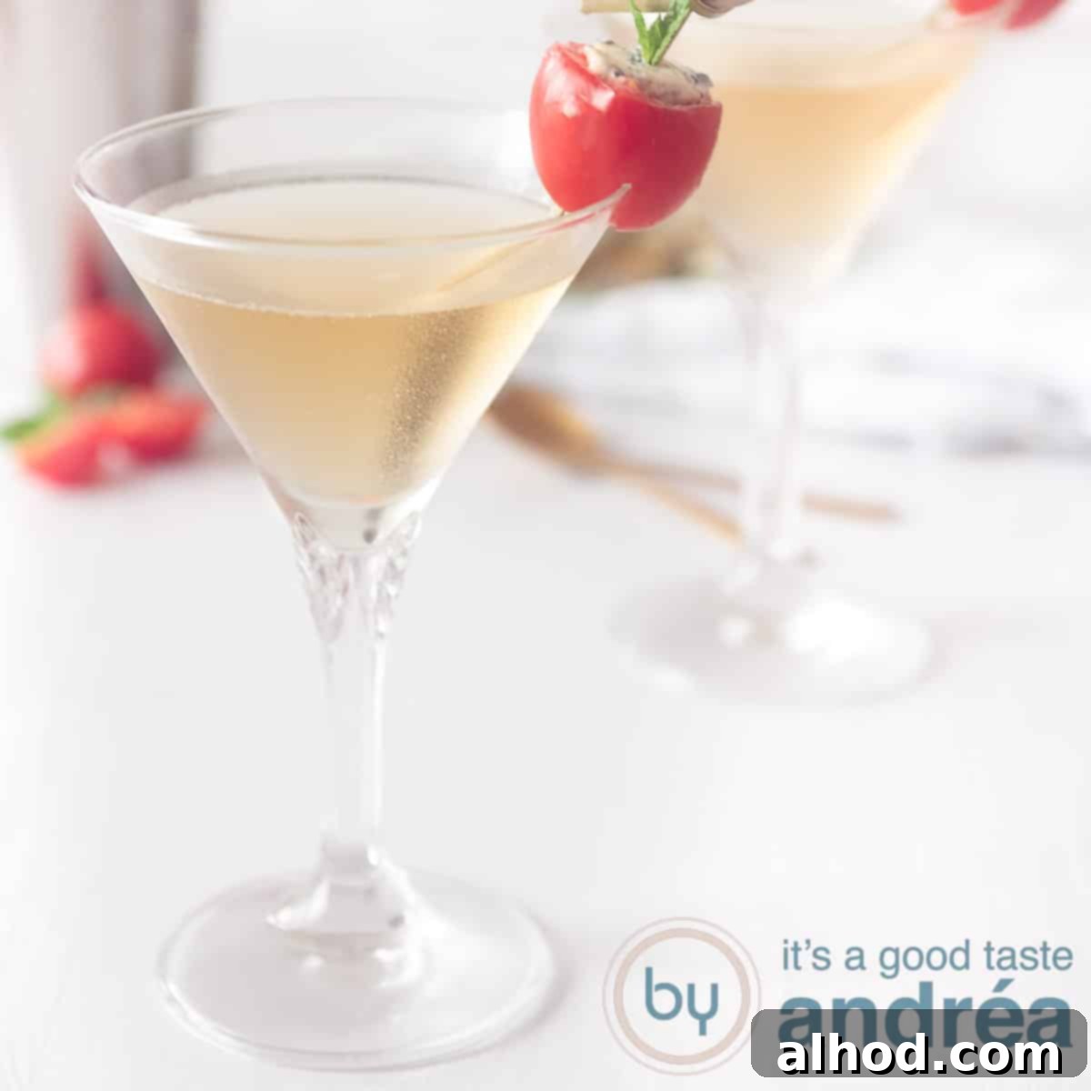 Sparkling Sips to Welcome the New Year 7 A square photo with two cocktail glasses filled with a basil martini cocktail. On a white background a cherry tomato as garnish
