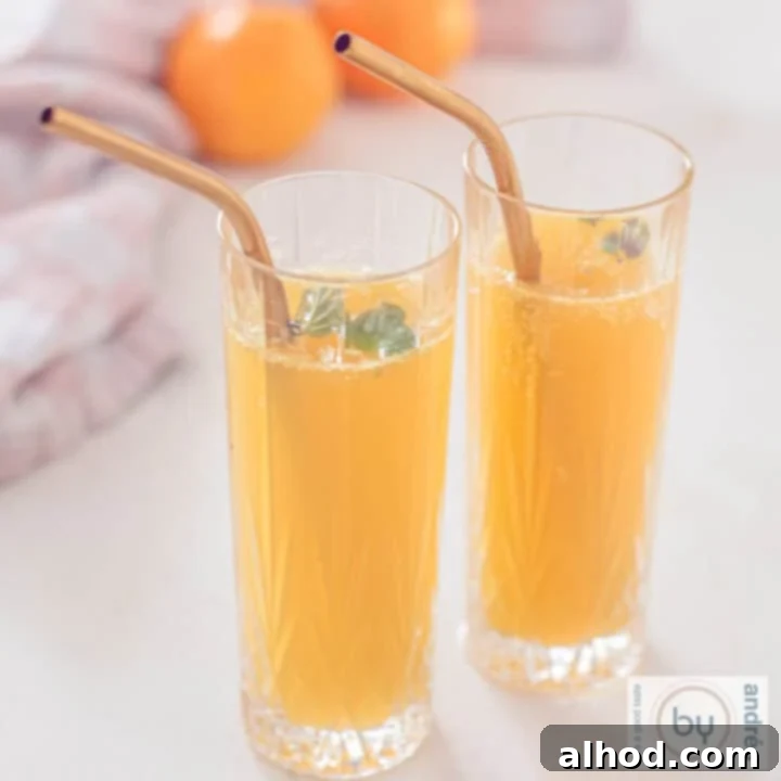 A square photo of two glasses with mandarin champagne cocktail a golden straw. Two mandarins in the background, portraying a bright and zesty mimosa.