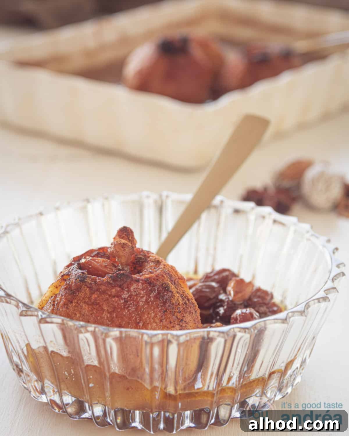 Two perfectly baked stuffed apples with a rich caramel sauce in a glass bowl.