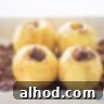 Stuffed apples on a bed of raisins and water in a white baking dish