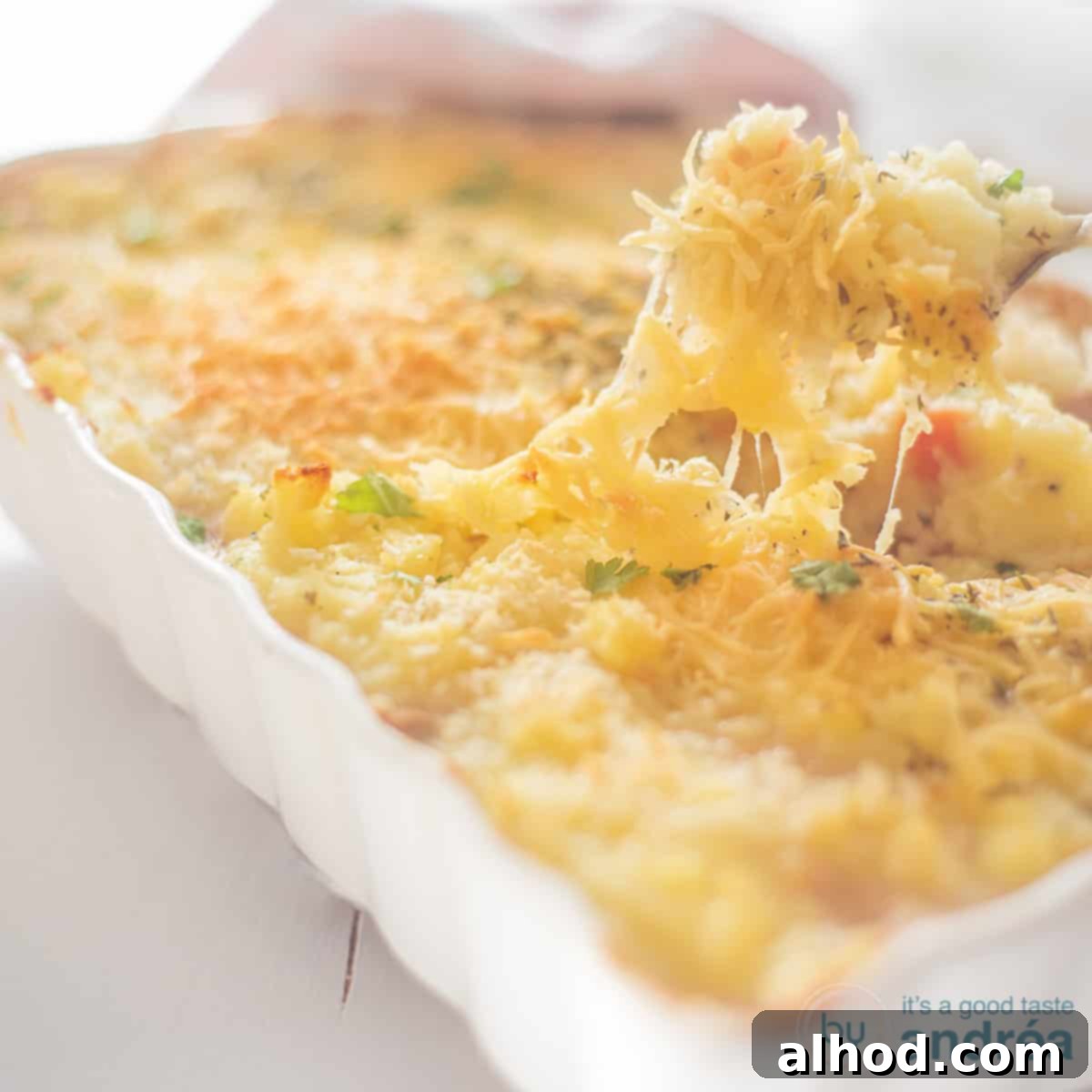 Sea Shepherd's Pie 4 A square photo with an oven dish filled with potato casserole with tuna. A spoon takes a bite of the cheesy top.