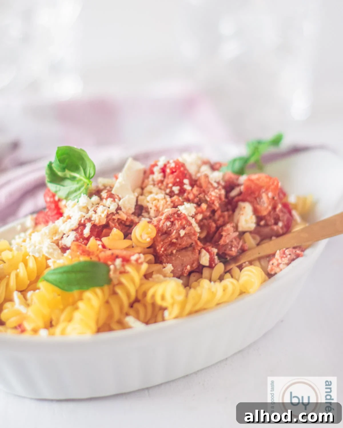 20-Minute Mediterranean Tuna Feta Pasta 2 A white oven dish filled with fusilli pasta, tuna, fresh tomato sauce, and crumbled feta cheese, ready to serve.