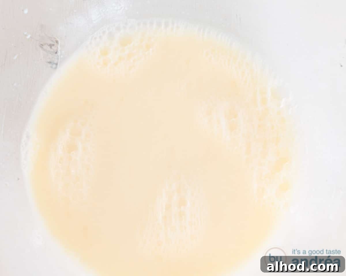 Easy Dairy-Free Chocolate Cupcakes 5 Liquid ingredients like soy milk, vanilla extract, flaxseed oil, applesauce, and apple cider vinegar are being beaten together until light and fluffy in a clear glass bowl, preparing them for the cupcake batter.