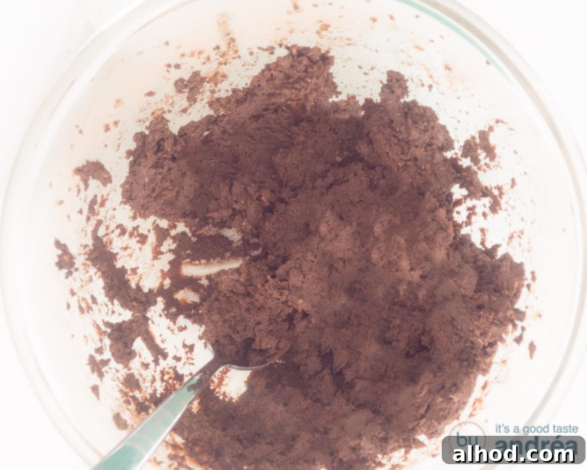 Easy Dairy-Free Chocolate Cupcakes 8 Ingredients for the vegan chocolate frosting, including plant-based butter, confectioners' sugar, cocoa powder, vanilla extract, salt, and soy milk, being vigorously mixed in a large bowl to achieve a light and fluffy consistency.