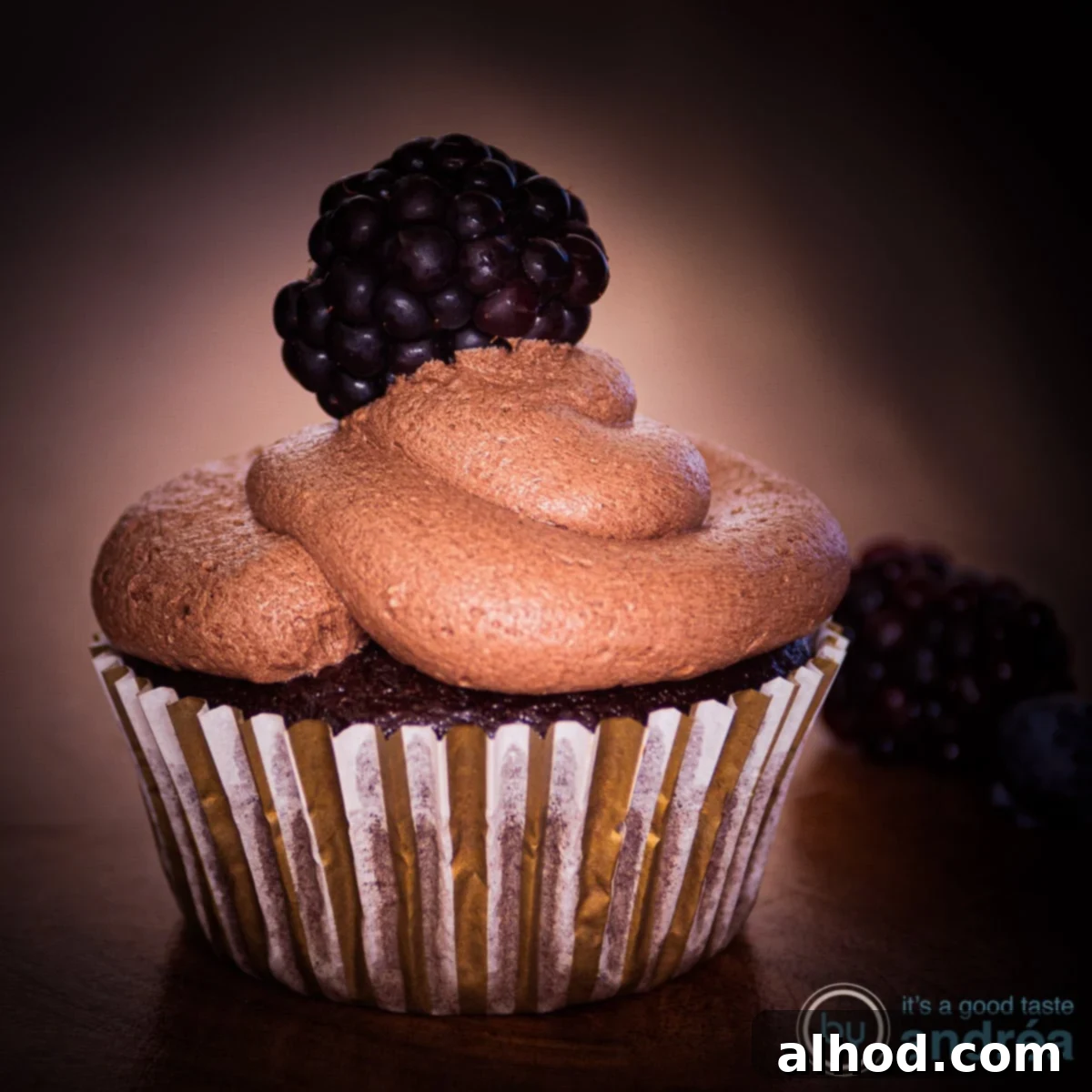 Easy Dairy-Free Chocolate Cupcakes 10 A square photo with a rich chocolate cupcake in the middle, decorated with a creamy topping, presented in warm brown tones.