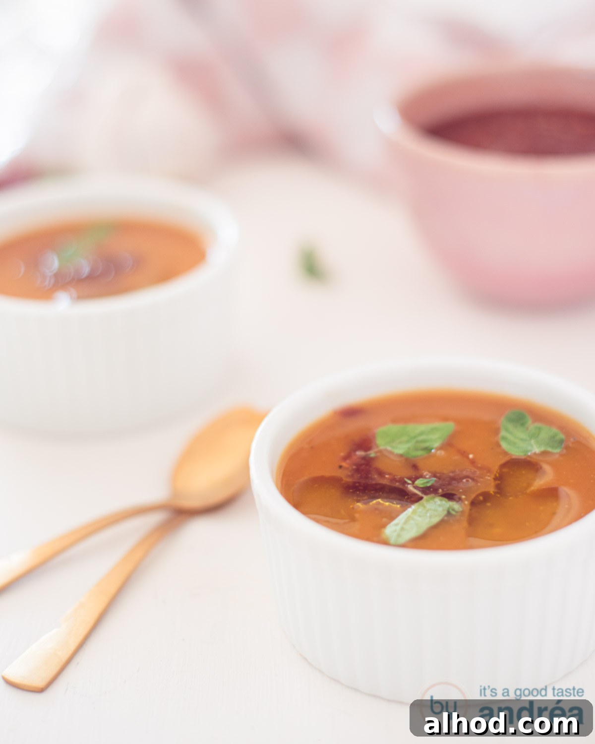 Wholesome Kickin' Pumpkin Warmth 4 Pumpkin soup with spicy salsa in two white bowls behind each other. Two golden spoons on the left.
