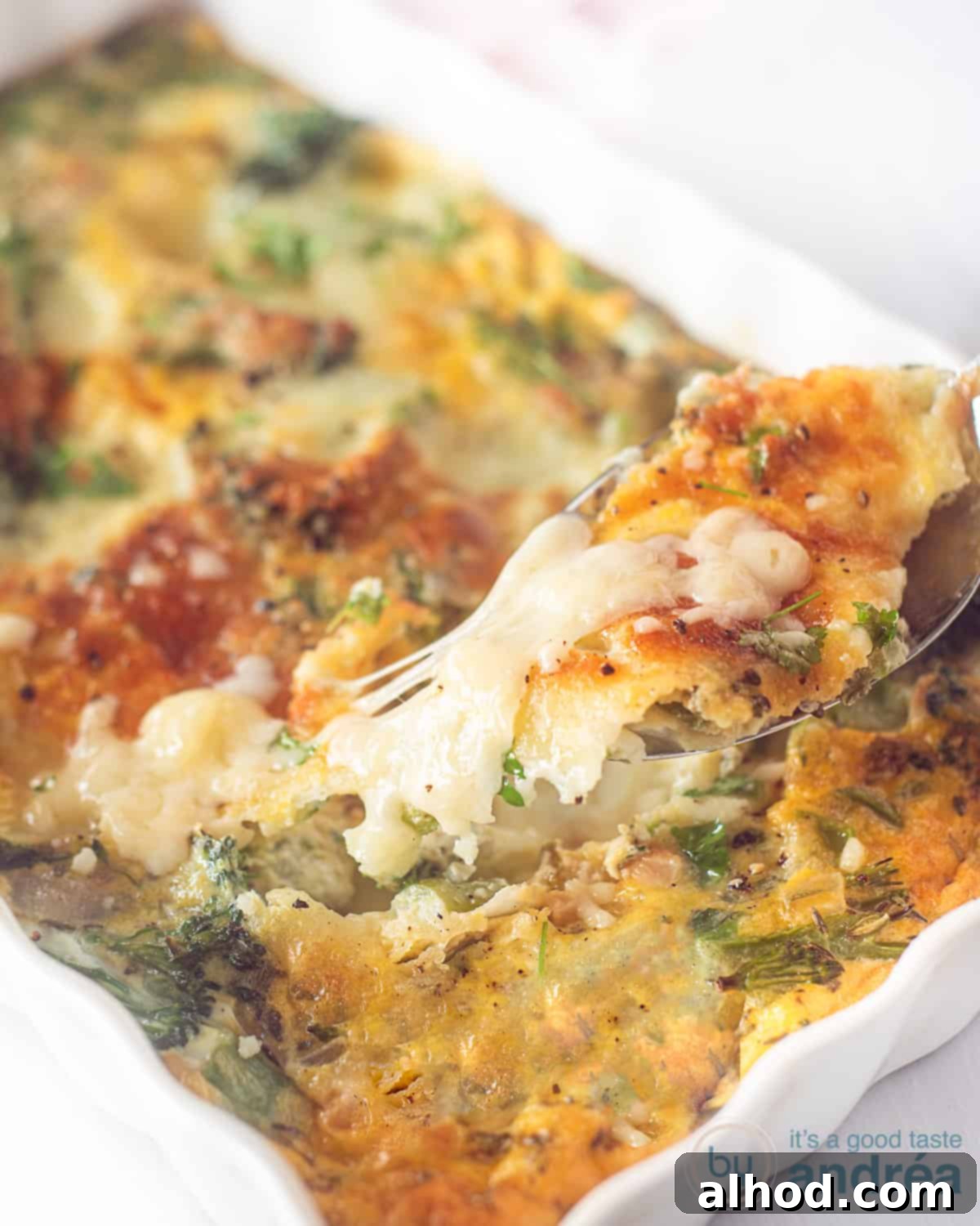 Herby Broccoli Frittata with Melted Mozzarella 2 A white casserole dish filled with a golden-brown frittata featuring broccoli and gooey mozzarella. A spoon is taking a serving, revealing stretchy melted cheese.