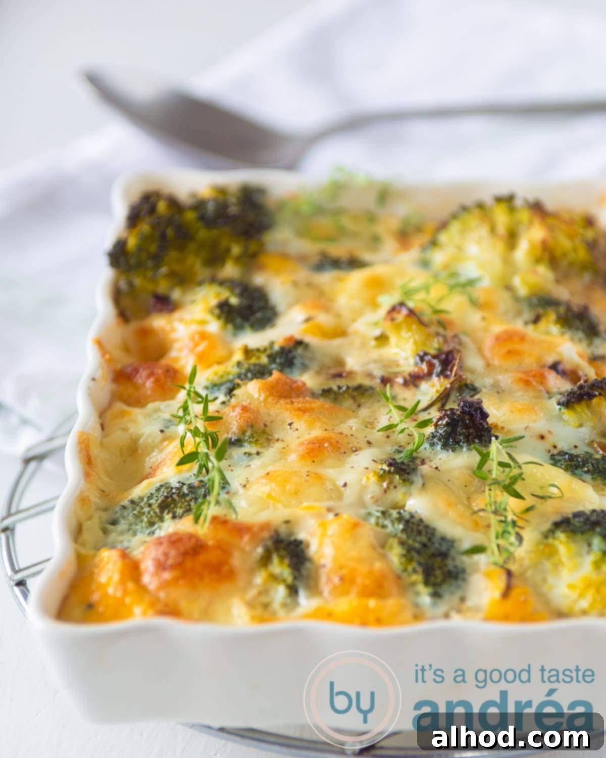 Broccoli frittata with Mozzarella in a white casserole dish on a white background. In the back a spoon is visible.